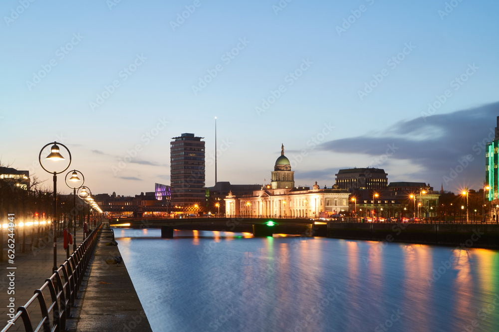 Long exposure of a river with illuminated buildings at dusk with almost clear sky