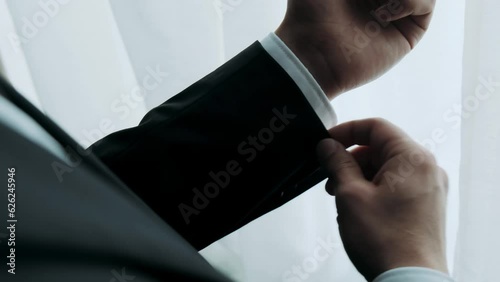 businessman straightens cuffs on the sleeves of his jacket
