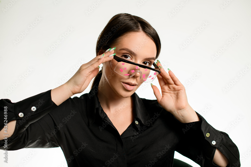 Woman brunette with green french manicure posing holding decorated protective glasses on her face Woman brunette with green french manicure posing holding decorated protective glasses on her face
