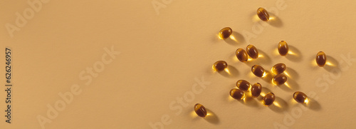 Diet, nutrition, healthy eating concept. Little oil filled yellow softgels capsules of food supplements on beige background.