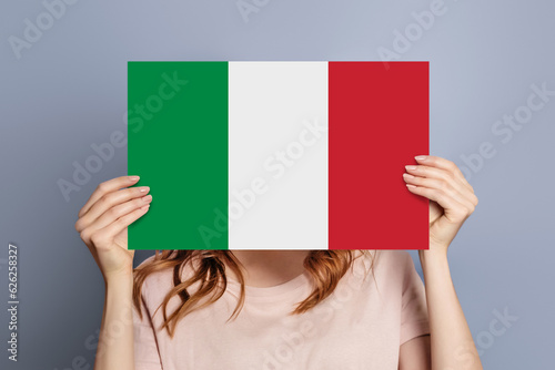 Student girl holds blank white speech bubble with italian flag isolated over grey background photo