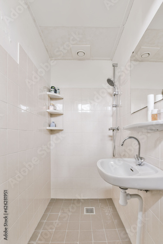 a bathroom with white tiled walls and beige tiles on the floor  there is a small sink in the corner