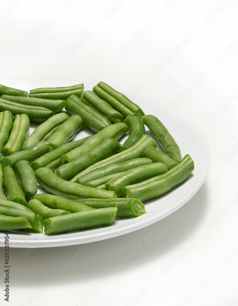 Fresh chopped green beans in a round plate, on a white background. 
