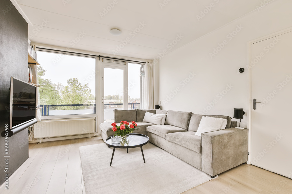Fototapeta premium a living room with a couch, coffee table, tv and large window looking out onto the street in london
