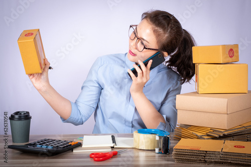 Asian woman owned business SME entrepreneur of Young Asian women working with Boxs laptop and phone for Online seller shopping at home