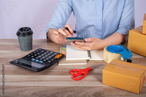 Asian woman owned business SME entrepreneur of Young Asian women working with Boxs laptop and phone for Online seller shopping at home