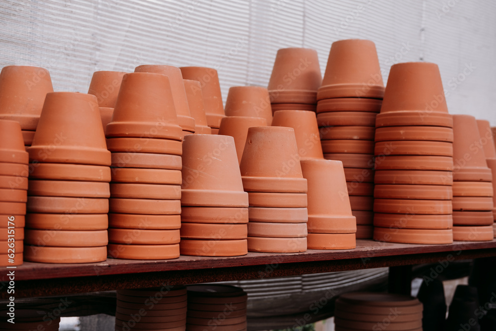 Stacked terracotta flower pots on the shelves at the garden center Stacked terracotta flower pots on the shelves at the garden center