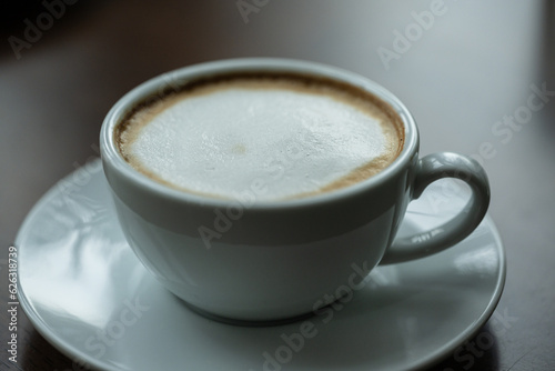Top view white cup of hot coffee latte on wood background in restaurant.Top view with copyspace for your text.