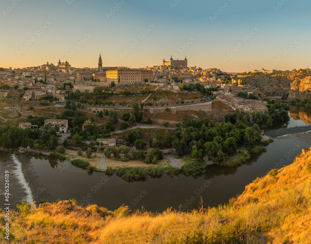 Sunset photo of the medieval walled city of Toledo, Spain. Golden light oh tops of buildings, including the Alcazar.