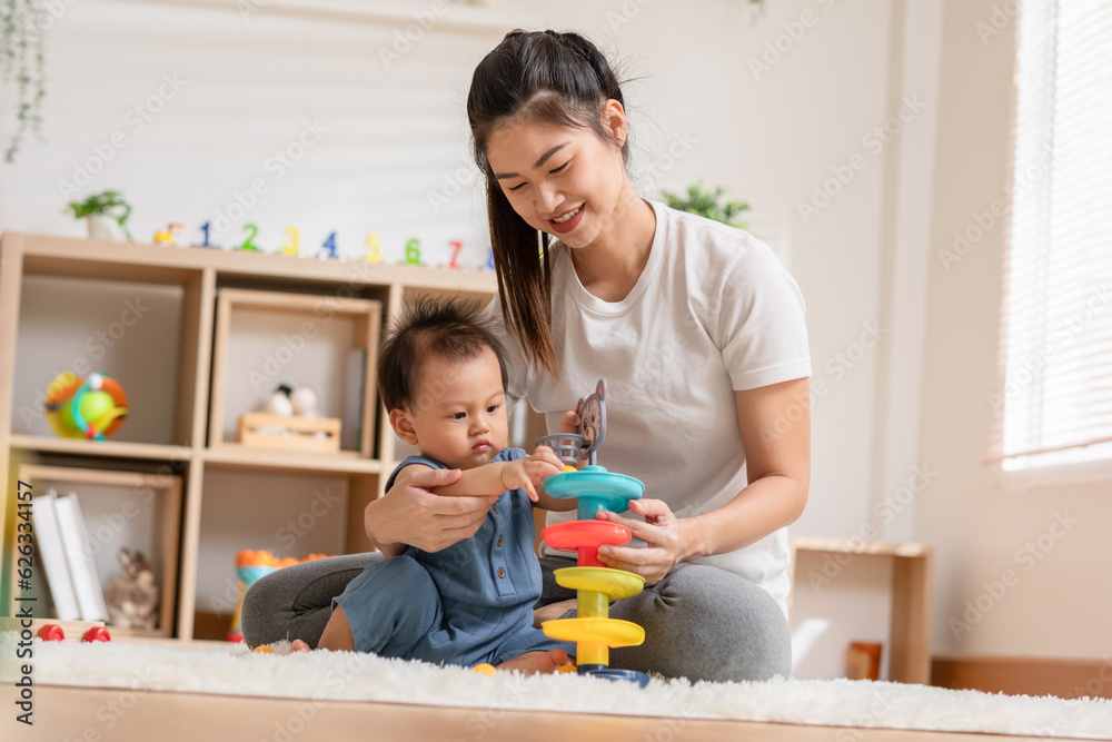 Asian mom teaching baby boy learning and playing toys for development skill at home or nursery room. Happiness mother and baby spending time together at warmth place. Good moment with mom and baby Asian mom teaching baby boy learning and playing toys for development skill at home or nursery room. Happiness mother and baby spending time together at warmth place. Good moment with mom and baby