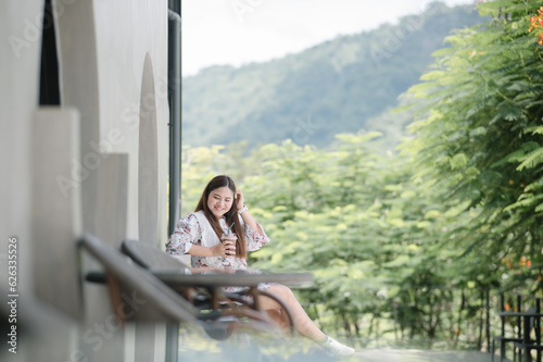 Portrait of a happy Asian woman drink water and eat cake in a coffee shop, nature background.