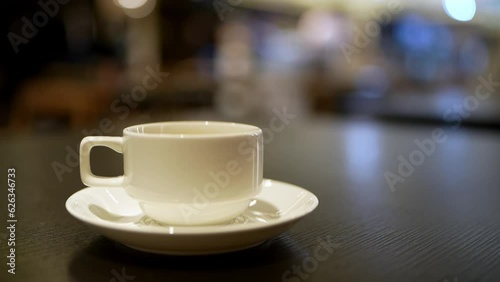 Hot cup of coffee with steam on a blurry background of people passing by, eating breakfast at a hotel.