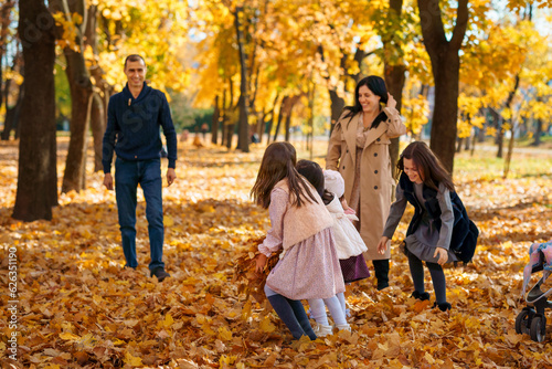 portrait of a big family in autumn city park, happy parents and children playing together and throwing yellow leaves, beautiful nature, bright sunny day