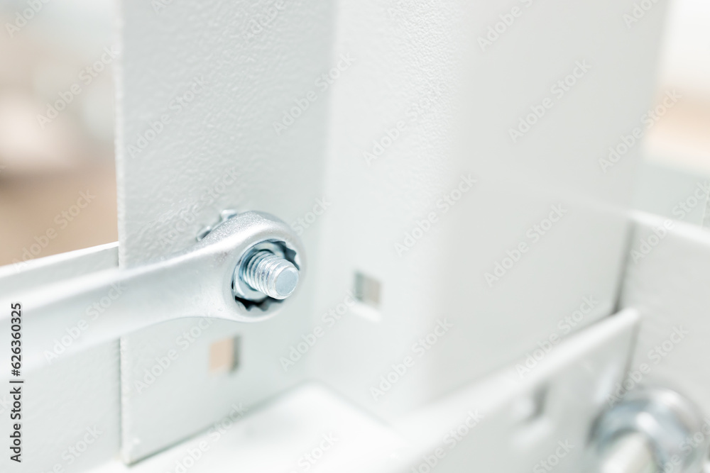 Obraz premium small depth of field on the wrench at the moment of tightening the nut on the metal rack