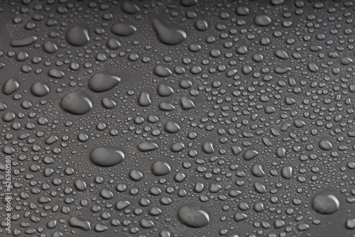 water droplets of various shapes on a black surface