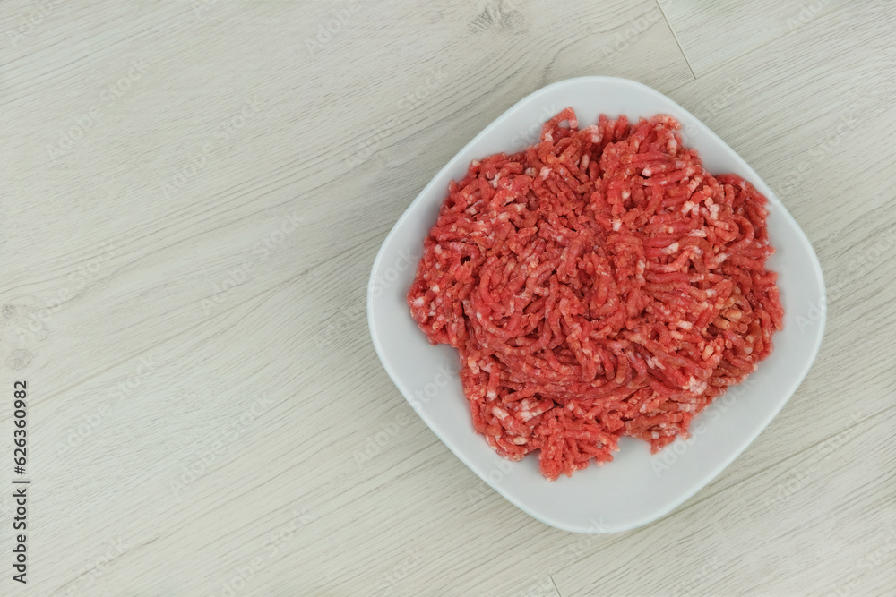 Bowl of mince on wooden background. Homemade minced meat comes out of the meat grinder. Cooking a burger. Bowl of mince on wooden background. Homemade minced meat comes out of the meat grinder. Cooking a burger.