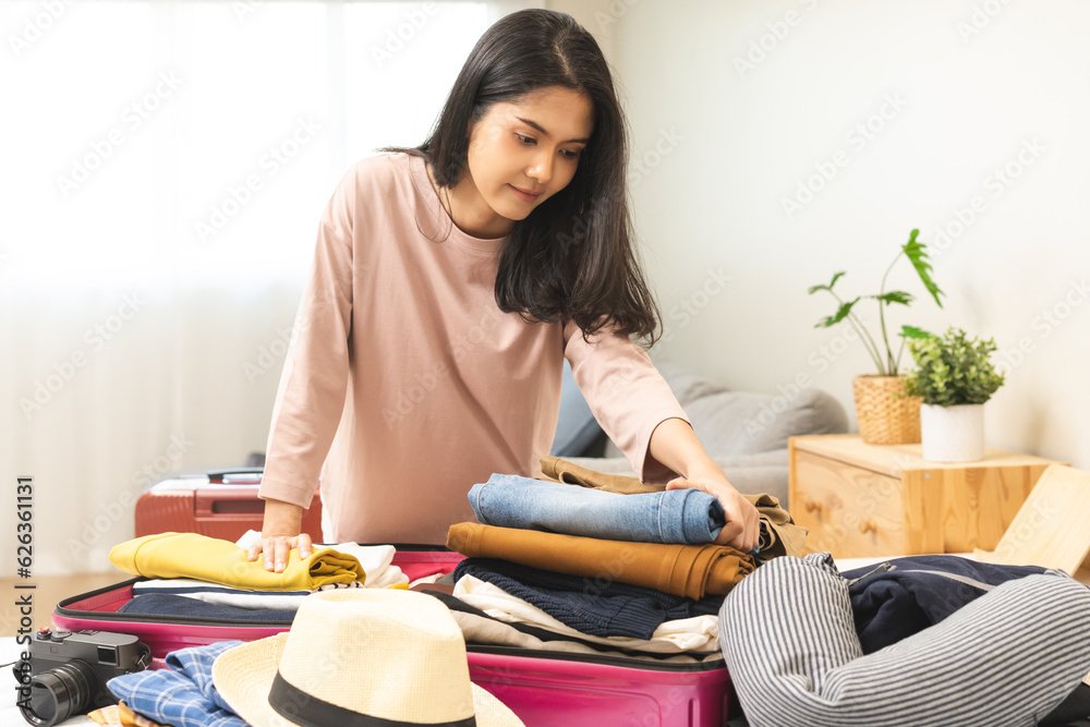 Travel concept, happy asian young woman hand preparing packing luggage bag for summer vacation trip on bed at home, pack her clothes and stuff, objects into bag suitcase for a new journey for leisure. Travel concept, happy asian young woman hand preparing packing luggage bag for summer vacation trip on bed at home, pack her clothes and stuff, objects into bag suitcase for a new journey for leisure.