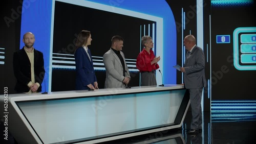 Funny charismatic host talking to the contestants during recording of a fictional morning family game show