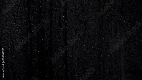Drops on misty window with runny drops of water with a black background