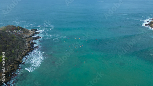Above Carrizalillo beach at Puerto Escondido, Oaxaca, Mexico: aerial shot of surfers riding turquoise waves