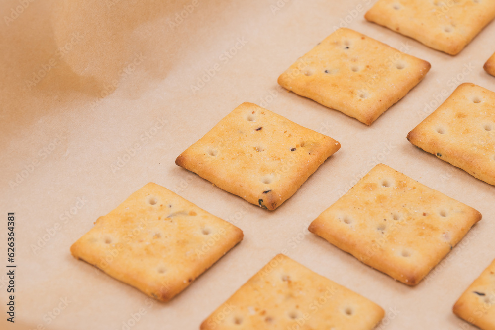 Spicy square crackers on parchment paper. Salty crackers closeup. Macro shot. Spicy square crackers on parchment paper. Salty crackers closeup. Macro shot.