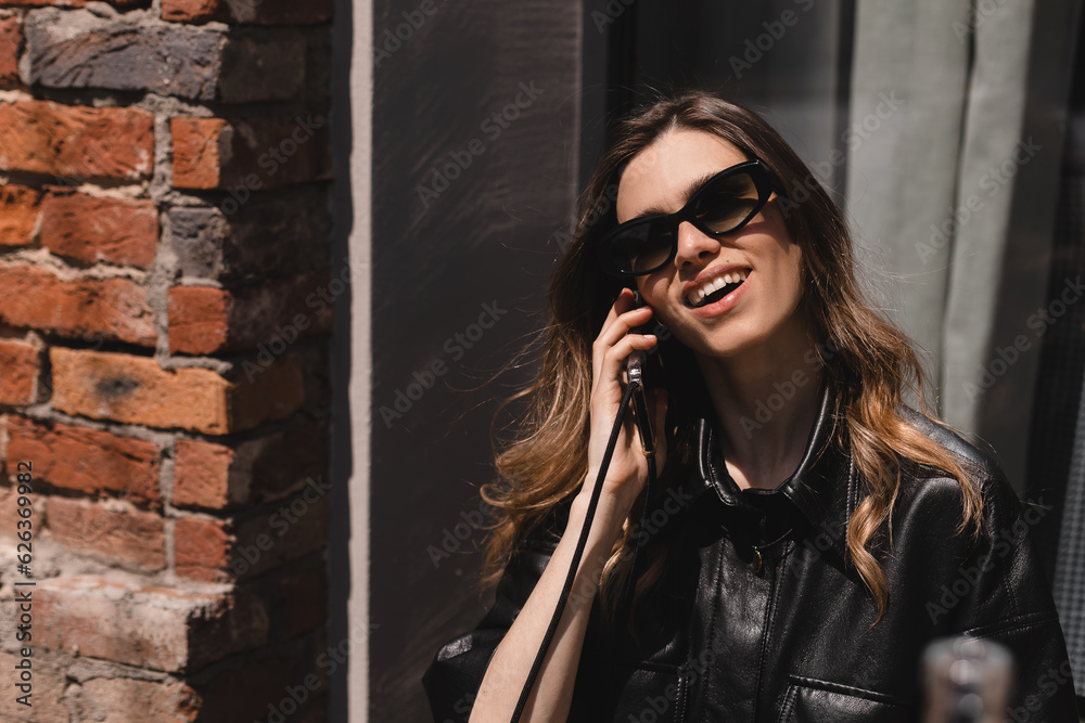 Cheerful hipster girl in glasses with curly hair having friendly mobile conversation enjoying good news sitting in cafe, attractive young woman in casual wear spending free time talking on smartphone. Cheerful hipster girl in glasses with curly hair having friendly mobile conversation enjoying good news sitting in cafe, attractive young woman in casual wear spending free time talking on smartphone.