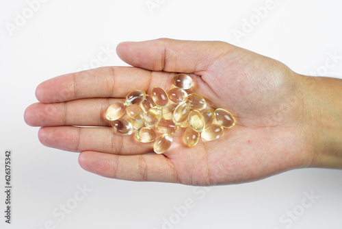D3k2 tablets held in the hand on a white background, golden capsules, dietary supplement