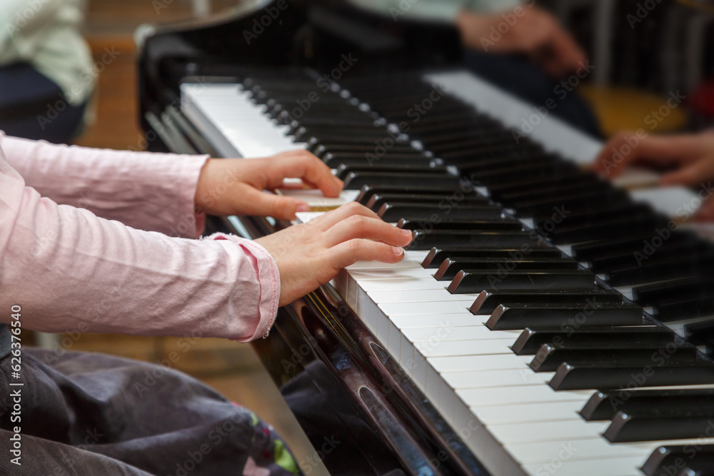 Fototapeta premium A child learns to play the piano in the lessons at a music school.