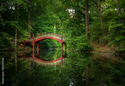 Ornate wooden bridge over very calm Crim Dell pond on campus of William and Mary college in Williamsburg Virginia photo
