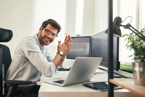 Young and successful. Happy bearded trader in formal wear and eyeglasses looking at camera and smiling while sitting in his modern office.