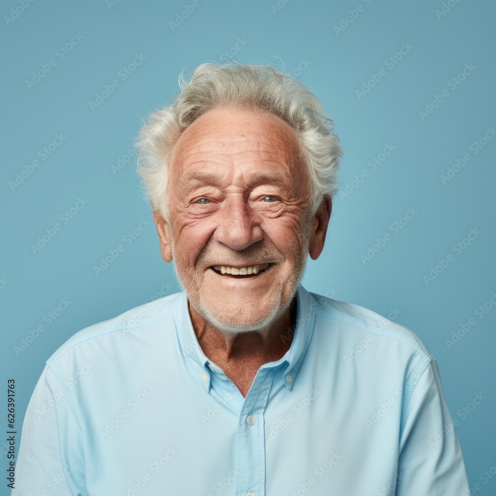 Portrait of a smiling elderly man with gray hair. Closeup face of a handsome Caucasian old man looking at the camera on a blue background. Front view of a happy European senior man in a blue shirt. Portrait of a smiling elderly man with gray hair. Closeup face of a handsome Caucasian old man looking at the camera on a blue background. Front view of a happy European senior man in a blue shirt.