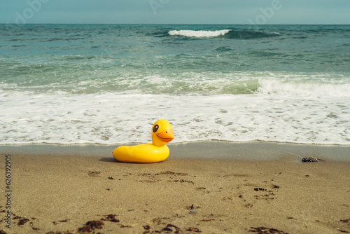 lifebuoy yellow duck on the sand on the beach on a summer day