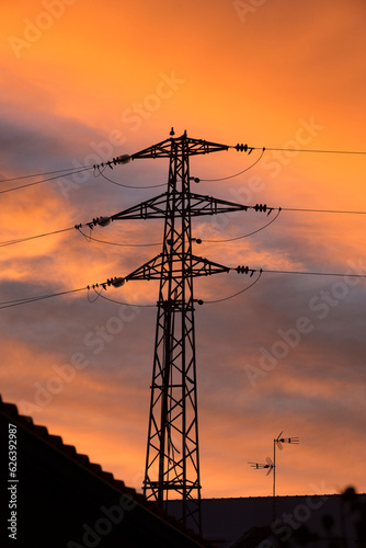 Detalhe da silhueta de poste de eletricidade alta tensão fundo amarelado de sunset.  photo