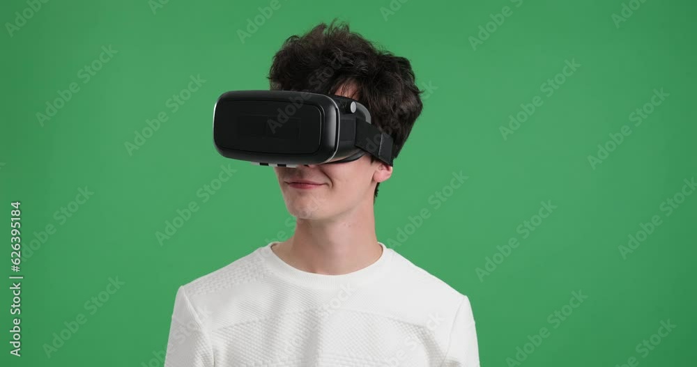 Caucasian man as he dons a VR headset against a vibrant green background. Man with infectious smile and sense of wonder as he explores a virtual environment using cutting-edge technology. Caucasian man as he dons a VR headset against a vibrant green background. Man with infectious smile and sense of wonder as he explores a virtual environment using cutting-edge technology.