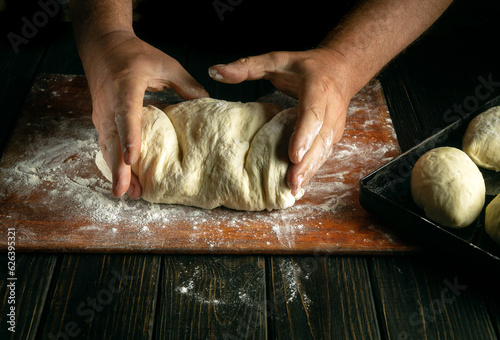 Fotografi Close-up of baker hands knead dough with flour for buns or pies