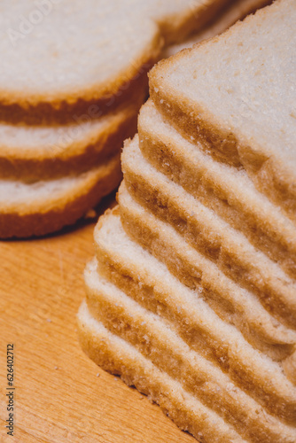 Sliced white bread with brown crust closeup on a wooden board.