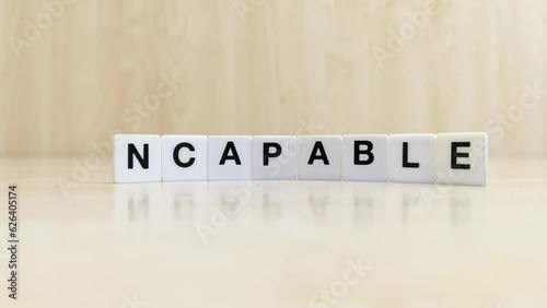 A hand changing the word incapable to capable with letters 