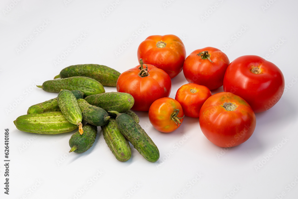 Fresh cucumbers and tomatoes on a white background. Plenty of fresh vegetables, healthy veggie food. Fresh cucumbers and tomatoes on a white background. Plenty of fresh vegetables, healthy veggie food.