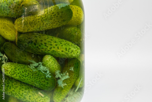A jar of pickled cucumbers close-up on a white background. Healthy food  pickled cucumbers in a jar. Detailed texture of cucumbers in a jar.