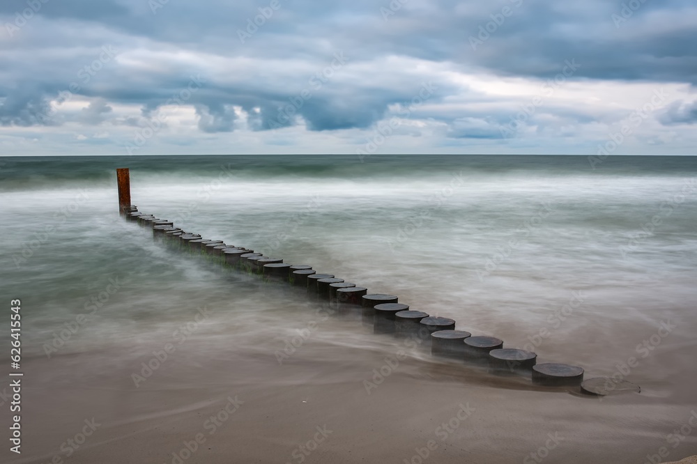 Beautiful holiday landscape by the Polish Baltic Sea. Sandy beach and clouds on a blue background in a holiday concept. Photo taken with shallow depth of field and long exposure time.