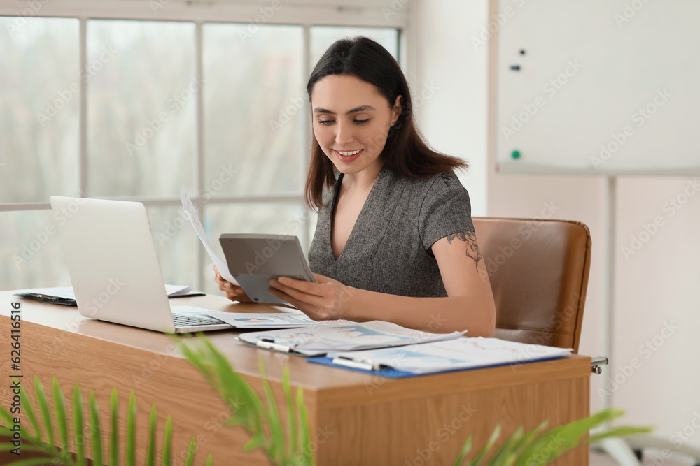 Female accountant working with document and calculator at table in office Female accountant working with document and calculator at table in office