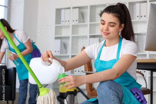 Female janitor pouring dete...