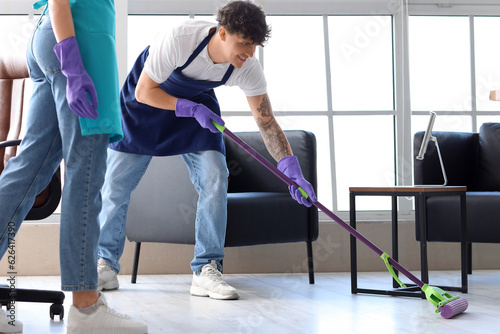 Male janitor mopping floor ...