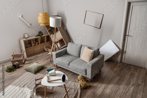 Sofa with tables and shelving units in messy living room © Pixel-Shot