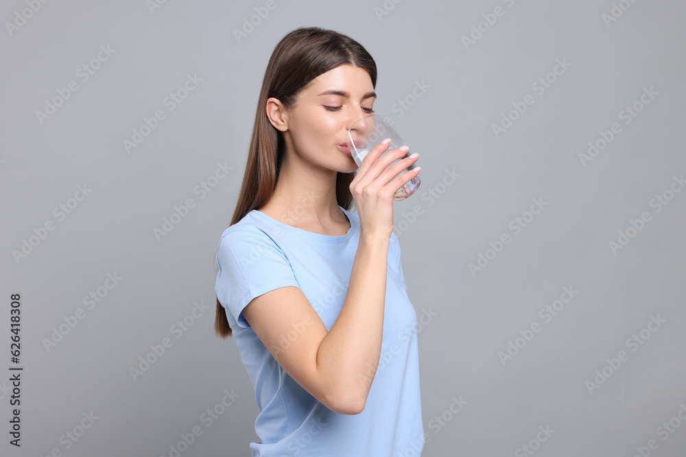 Healthy habit. Woman drinking fresh water from glass on grey background Healthy habit. Woman drinking fresh water from glass on grey background