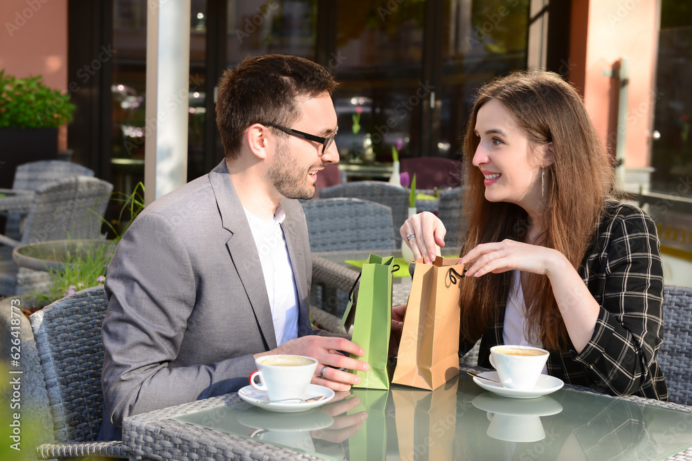 Young man giving present for his girlfriend in restaurant on sunny spring day Young man giving present for his girlfriend in restaurant on sunny spring day