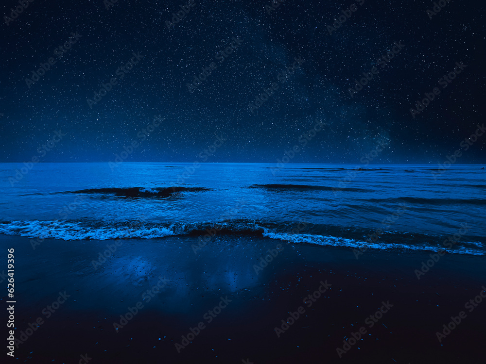 Sea waves rolling onto sandy beach under starry sky at night - obrazy, fototapety, plakaty 
