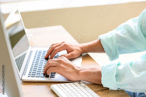 Male programmer working with laptop at table in office, closeup