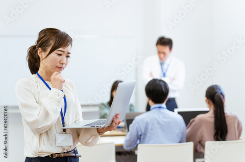 オフィス・会議室にいるパソコンを持ったビジネスウーマン・女性（困る・悩む） 