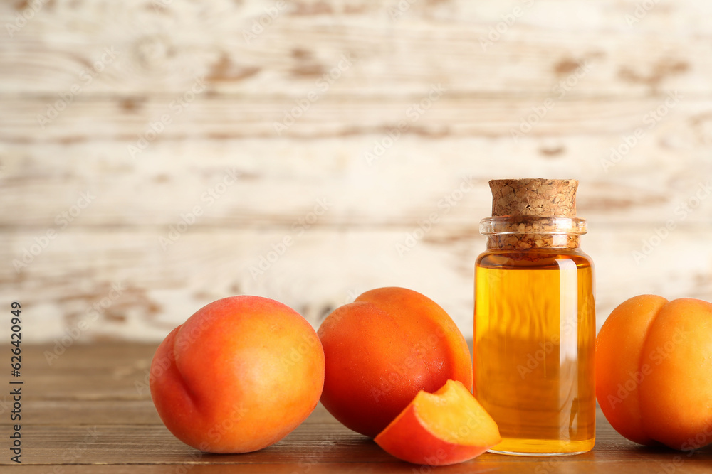Bottle with cosmetic oil and apricots on wooden table Bottle with cosmetic oil and apricots on wooden table